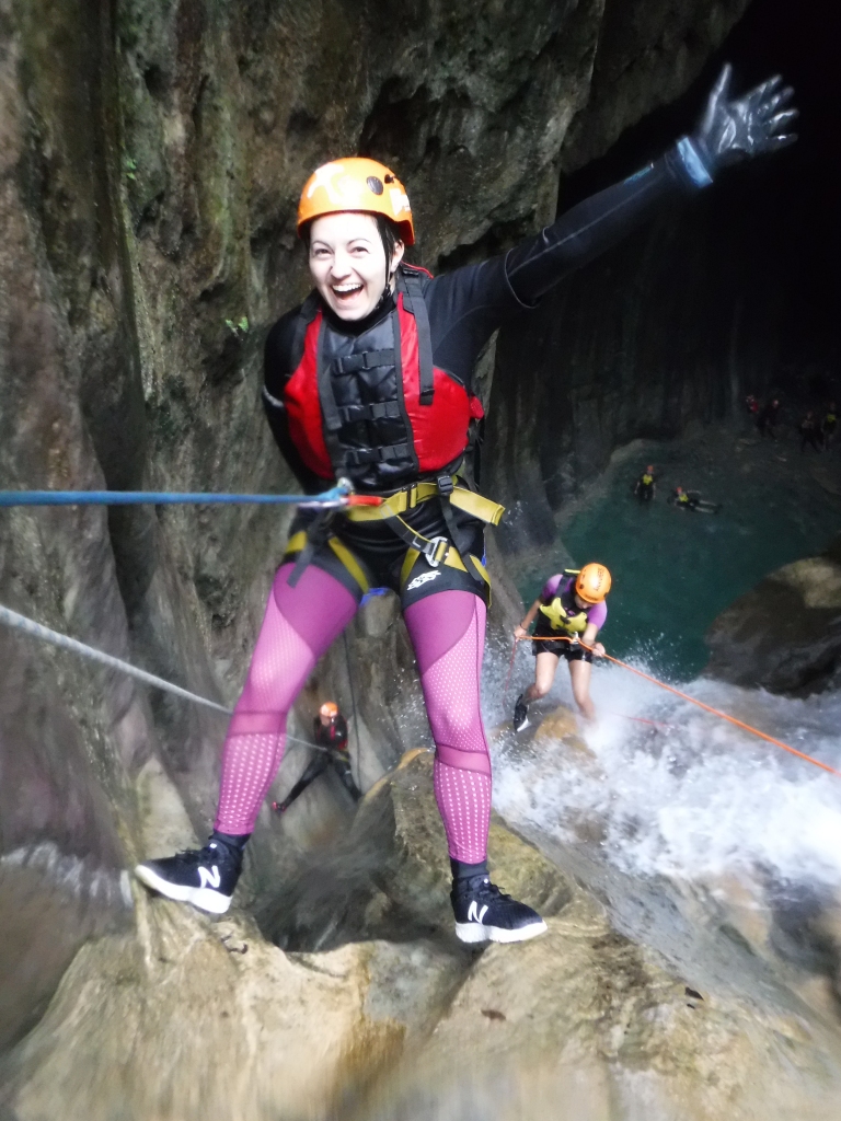 Sue rappelling down through a waterfall into a cave.